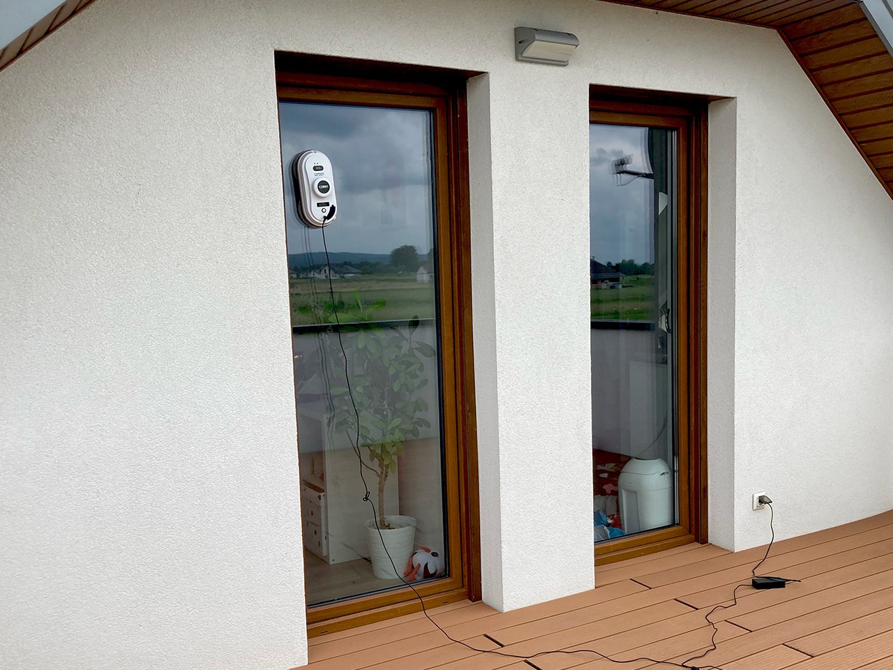 biały robot okienny myjący duże okno od zewnątrz